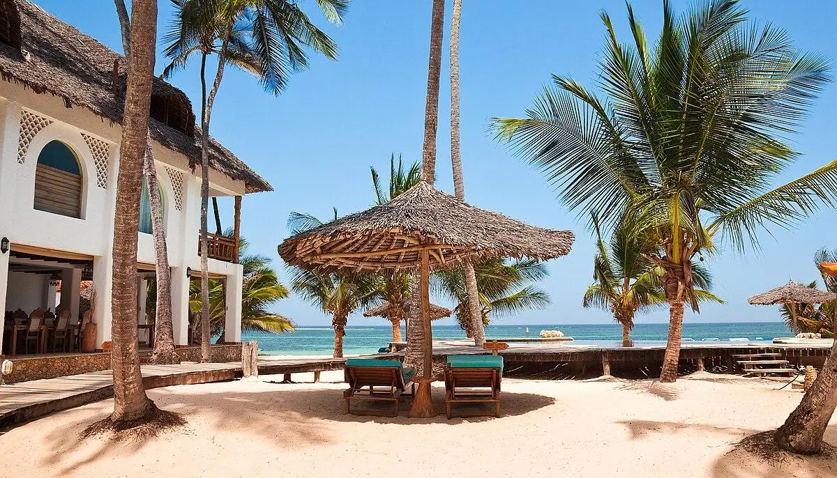 Luxury beachfront resort at Diani Beach, Kenya, with palm trees, thatched umbrellas, and ocean views.