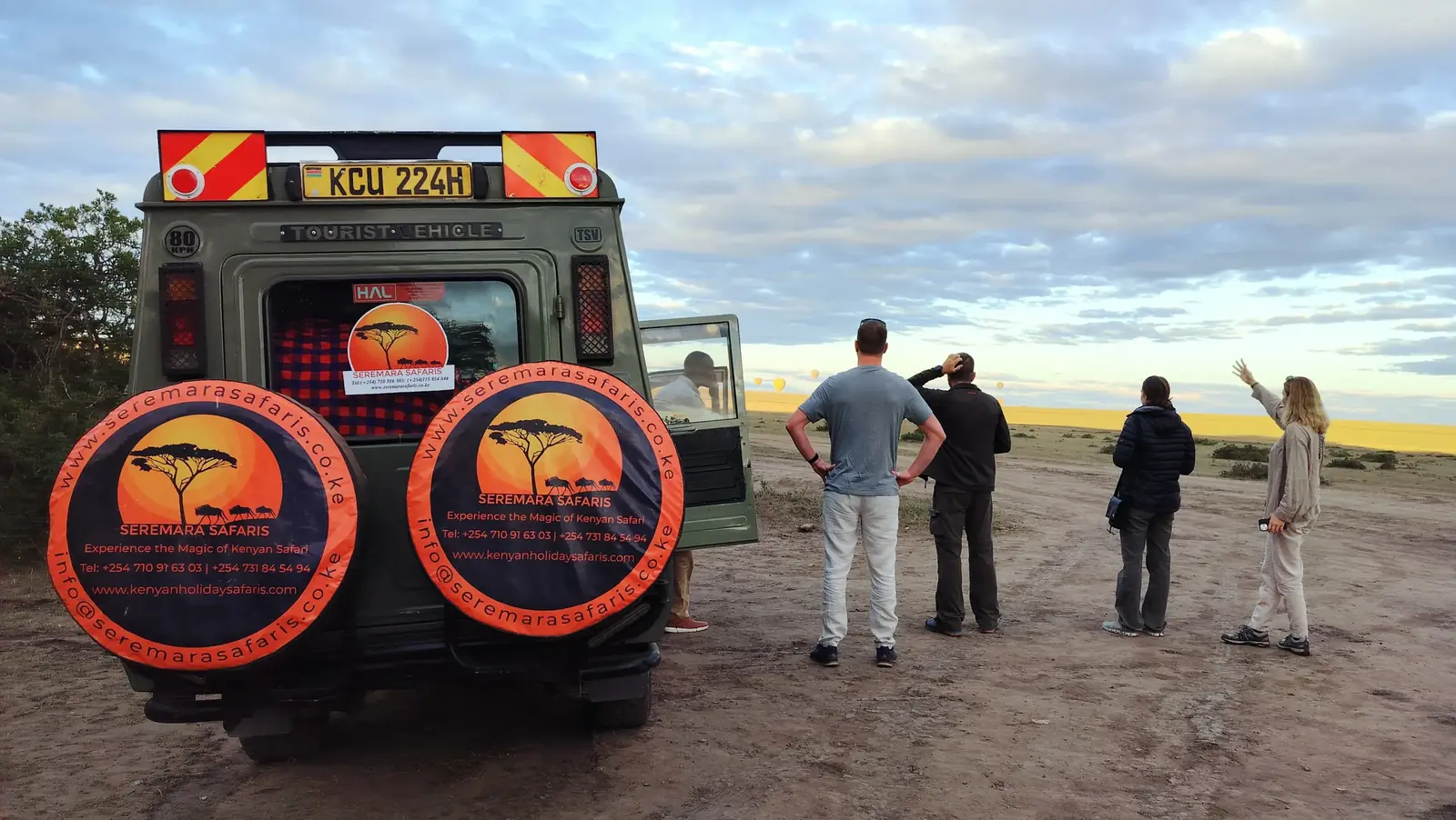 Guests on a Seremara Safaris game drive vehicle watching hot air balloons rise over the Masai Mara at sunrise