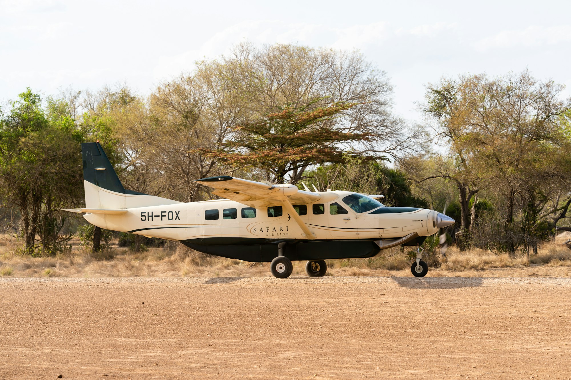 Small safari aircraft and game-drive vehicles at a Maasai Mara bush airstrip